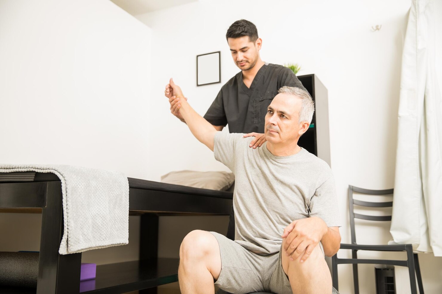 physiotherapist-helping-elderly-patient-with-hand-exercise-physiotherapy-clinic_662251-1734